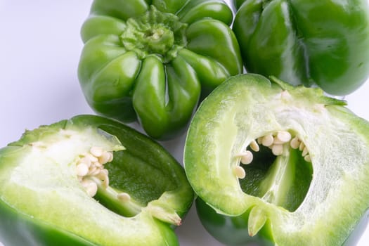 Fresh green bell peppers (capsicum) on a white background. Selective focus and crop fragment