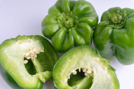 Fresh green bell peppers (capsicum) on a white background. Selective focus and crop fragment