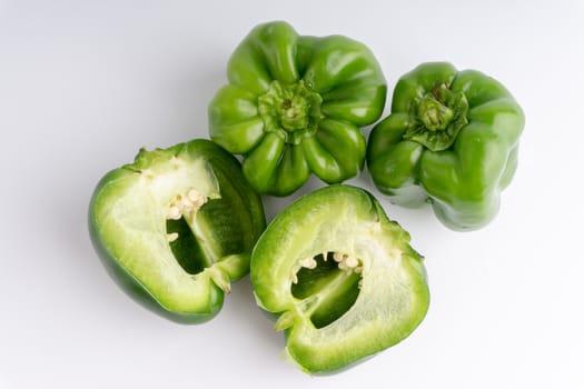 Fresh green bell peppers (capsicum) on a white background. Selective focus and crop fragment