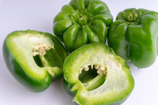 Fresh green bell peppers (capsicum) on a white background. Selective focus and crop fragment