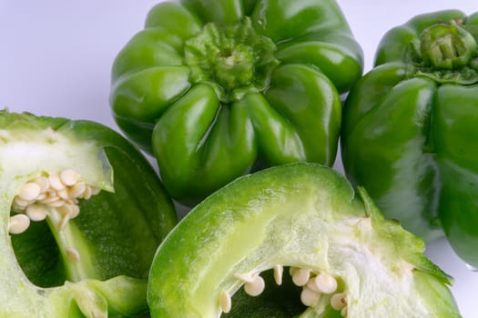 Fresh green bell peppers (capsicum) on a white background. Selective focus and crop fragment