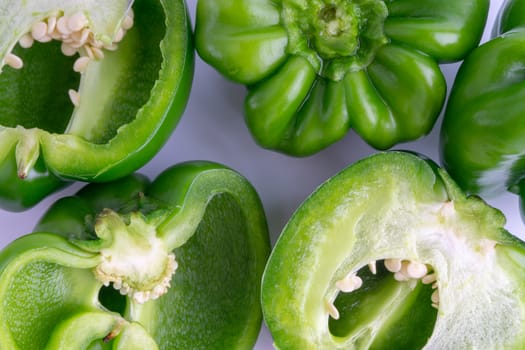 Fresh green bell peppers (capsicum) on a white background. Selective focus and crop fragment