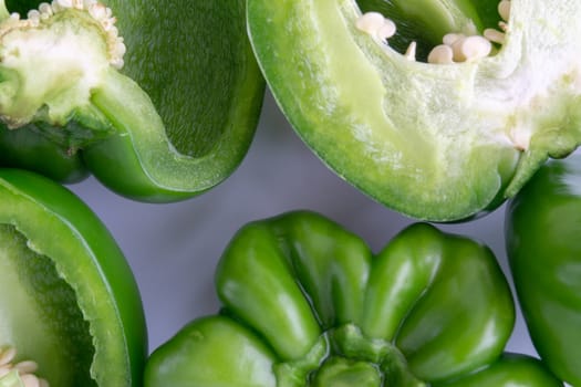 Fresh green bell peppers (capsicum) on a white background. Selective focus and crop fragment