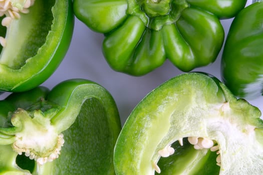 Fresh green bell peppers (capsicum) on a white background. Selective focus and crop fragment