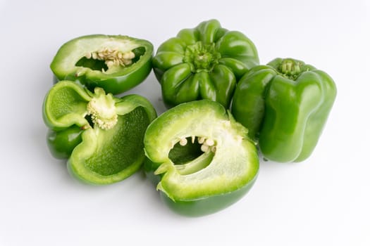 Fresh green bell peppers (capsicum) on a white background. Selective focus and crop fragment