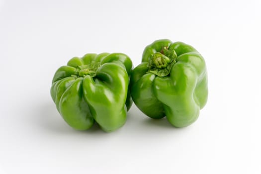 Fresh green bell peppers (capsicum) on a white background. Selective focus and crop fragment