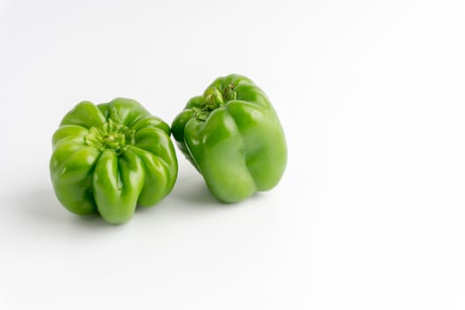 Fresh green bell peppers (capsicum) on a white background. Selective focus and crop fragment