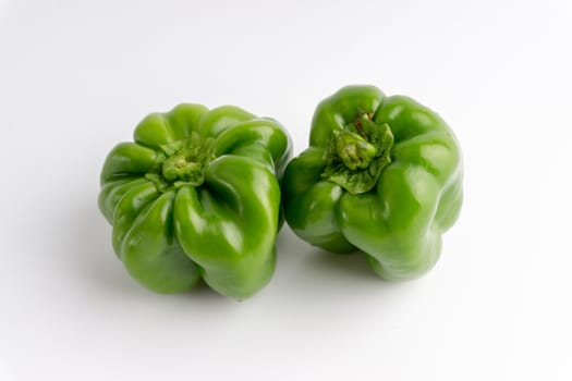 Fresh green bell peppers (capsicum) on a white background. Selective focus and crop fragment