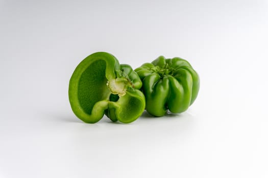 Fresh green bell peppers (capsicum) on a white background. Selective focus and crop fragment