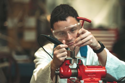 a repairman at a car repair shop adjusts a nut in a vise