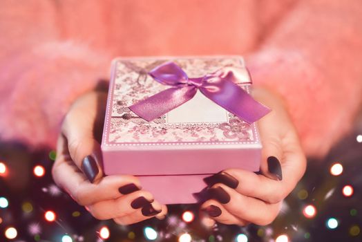 Female hand holding a pink gift box. The Valentines day and Christmas theme