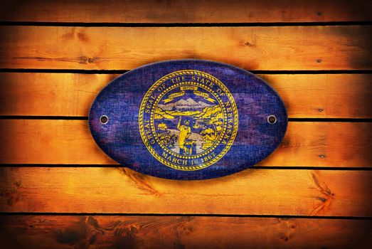 A Nebraska flag on brown wooden planks.