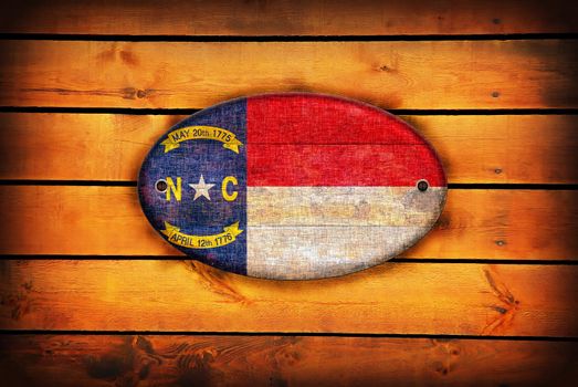 A North Carolina flag on brown wooden planks.