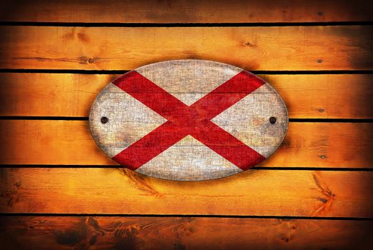 A Alabama flag on brown wooden planks.