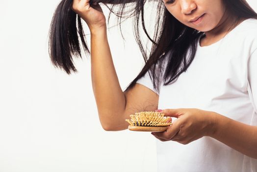 Asian woman unhappy weak hair her hold hairbrush with damaged long loss hair in the comb brush on hand and she looking to hair, studio shot isolated on white background, medicine health care concept