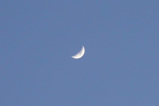 a small moon in the blue sky.