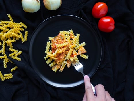 Fusilli Tomato Sauce chicken,Ingredients Tomatoes, Chicken, Garlic, Pepper, Onions, Is Italian food Placed on a Black plate
Black fabric background