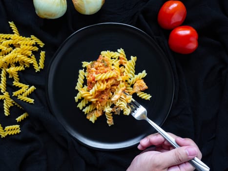 Fusilli Tomato Sauce chicken,Ingredients Tomatoes, Chicken, Garlic, Pepper, Onions, Is Italian food Placed on a Black plate
Black fabric background