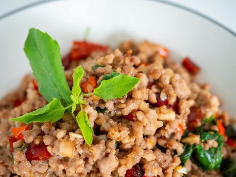 Stir fried basil with minced on a white plate,Thai food hot and spicy flavor. The ingredients are basil, garlic. Minced pork and Chili pepper,White background