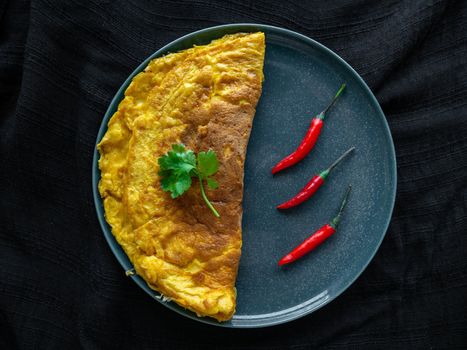 Omelette Thai food colors golden yellow and red chilies, placed on a green plate Decorated with coriander on the top of the egg,Black background