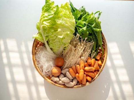 Ingredients Thai Sukiyaki Soup include Mushroom Sausage Pork ball Morning glory Chinese cabbage Vermicelli Celery Egg on basket,White Background