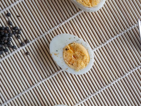 ฺBoiled egg topped with Cayenne pepper Pepper and Salt on a white dish,Egg colors white and yellow,Eat with bread