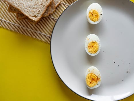 Boiled egg topped with Cayenne pepper Pepper and Salt on a white dish,Egg colors white and yellow,Eat with bread