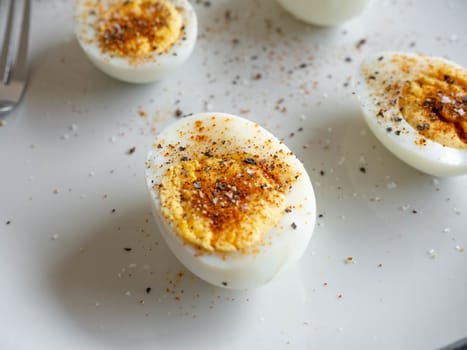 Boiled egg topped with Cayenne pepper Pepper and Salt on a white dish,Egg colors white and yellow,Eat with bread