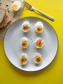 Boiled egg topped with Cayenne pepper Pepper and Salt on a white dish,Egg colors white and yellow,Eat with bread