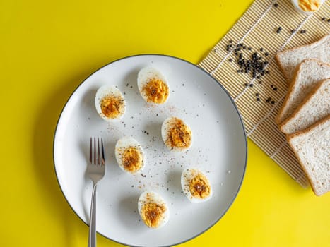 Boiled egg topped with Cayenne pepper Pepper and Salt on a white dish,Egg colors white and yellow,Eat with bread