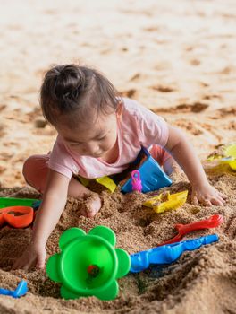 cute asian baby girl playing with beach toys on the beach