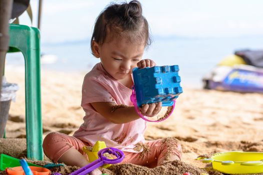 Cute asian baby girl playing with beach toys on the beach