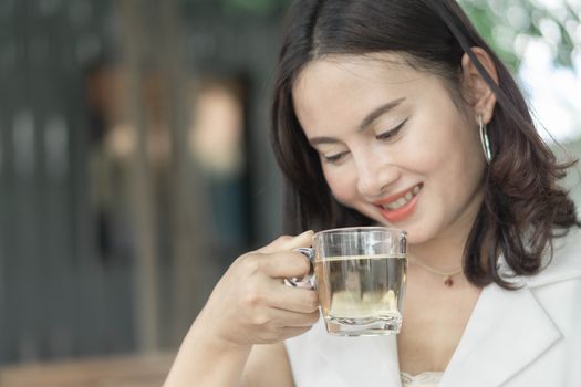 Close up woman drinking tea from glass with light in the morning, Selective focus