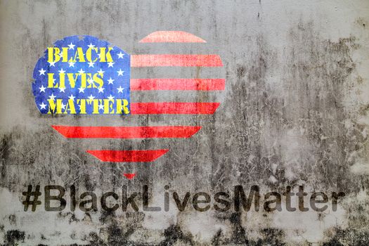 Black Lives Matter slogan hashtag liberation banner protestors heart stencil on American flag city street USA background old concrete wall