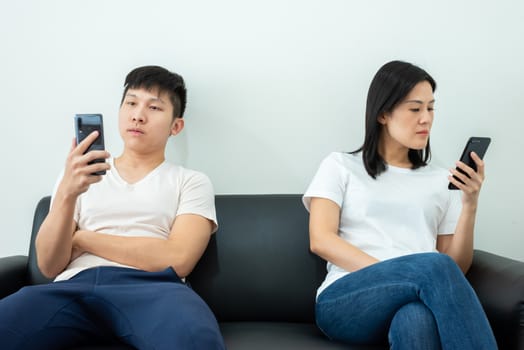 An Asian couple stays together and playing the phone with social distancing.