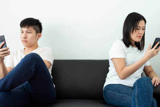 An Asian couple stays together and playing the phone with social distancing.