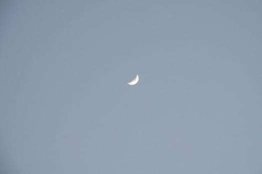 a small moon in the blue sky.