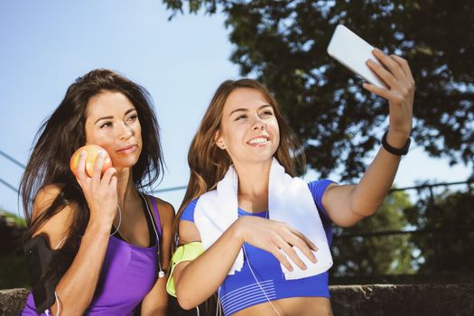 Millennials lifestyle concept - two sports girls take a selfie and smile while training outdoors on a sunny day ( vintage effect)