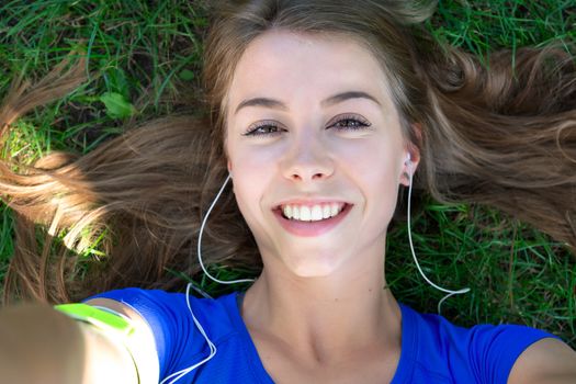 Beautiful fitness girl taking a selfie photo while resting after outdoors workout.