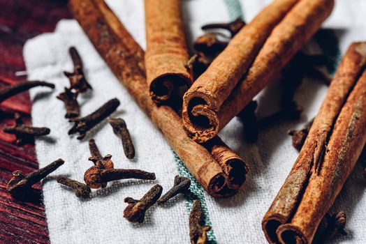 Cinnamon sticks and cloves on white kitchen towel