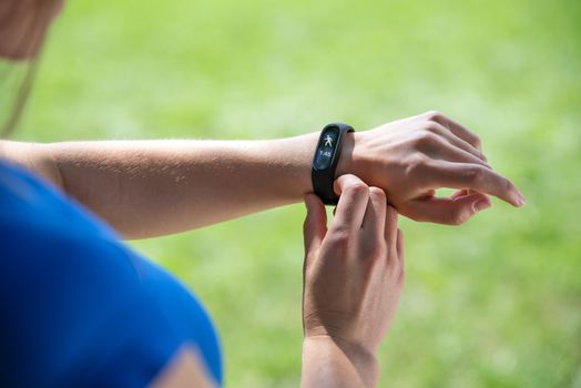 Modern sport gadget concept - young woman using a smartband and monitoring her workout in close-up (mixed).
