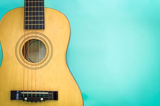 Acoustic guitar resting against a green background detail object