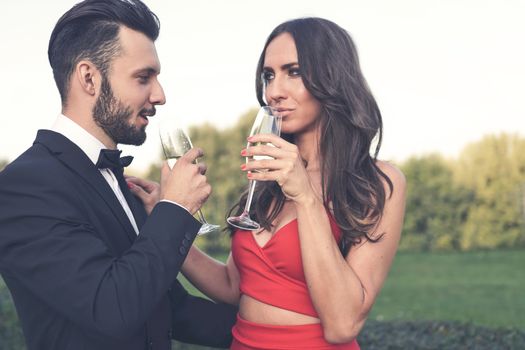 Happy couple of lovers with a glass of wine or champagne standing outdoors.