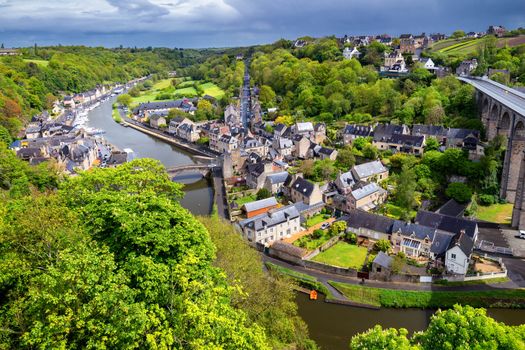 Beautiful view of scenic narrow alley with historic traditional houses and cobbled street in an old town of Dinan with blue sky and clouds. Brittany (Bretagne), France