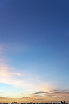 Portrait view of an early morning sky with tin and small clouds lighted by the vivid morning sunrise at the horizon