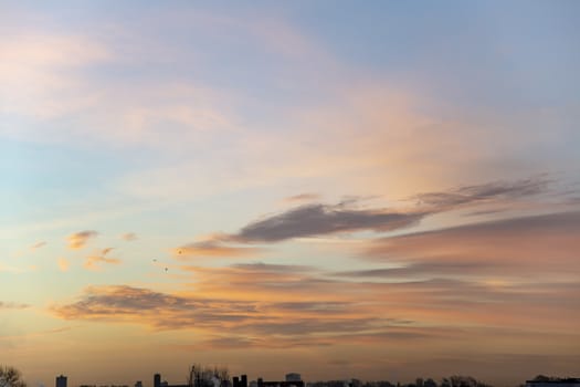 Portrait view of an early morning sky with tin and small clouds lighted by the vivid morning sunrise at the horizon