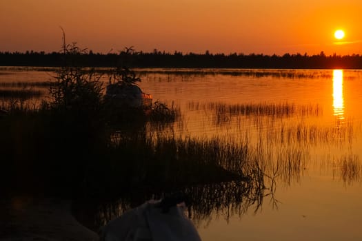 Orange is canaled over the water surface of the lake. Grass in the lake and the reflection of the sunset.