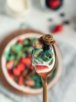 Trendy food - pancake cereal. Bowl of colorful mini cereal pancakes in spoon with milk. Tiny pancakes with natural color - green matcha, turquose spirulina, blue pea, red fragon fruit. Copy space