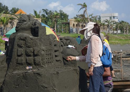 KAOHSIUNG, TAIWAN -- AUGUST 5, 2017: Artists work on sand sculptures at the 2017 Black Sand Beach festival on Chijin Island.