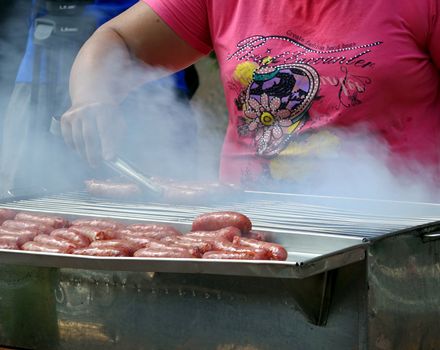 KAOHSIUNG, TAIWAN -- JULY 25, 2015: A female outdoor vendor cooks sausages on a charcoal grill.